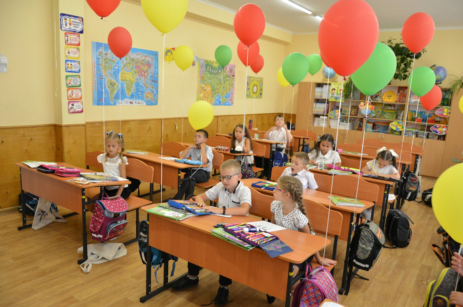 Двоє молодших школярів сидять за партою в святково прикрашеному класі